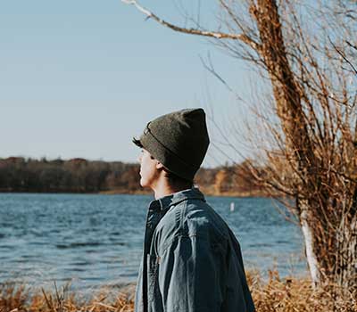Boy in branded hat overlooking lake