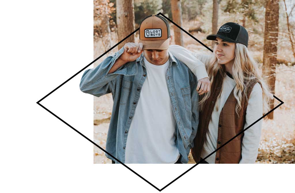 Young couple wearing hats with logos while walking in the woods