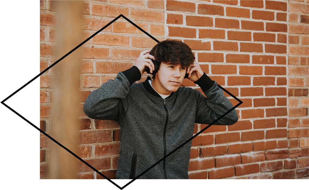 Young man with headphones by brick wall